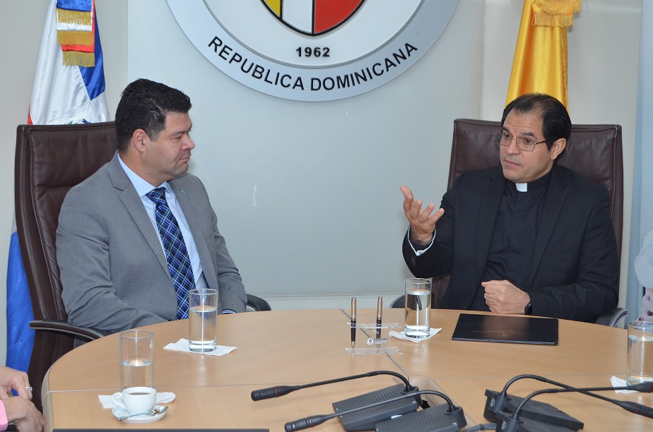 Negrón y el padre Secilio conversan previo a la firma del acuerdo.